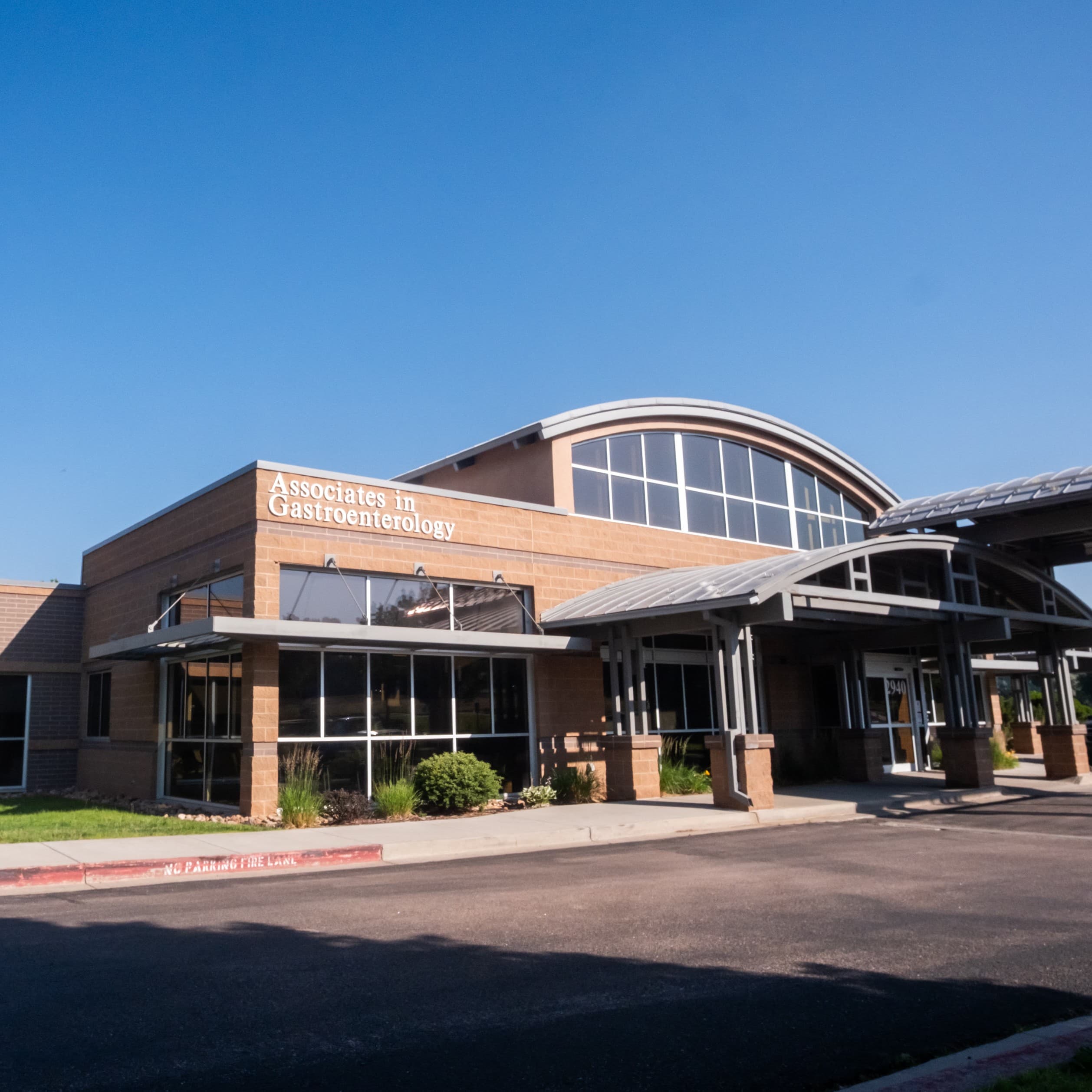 Exterior of an Associates in Gastroenterology medical office building under a clear blue sky.