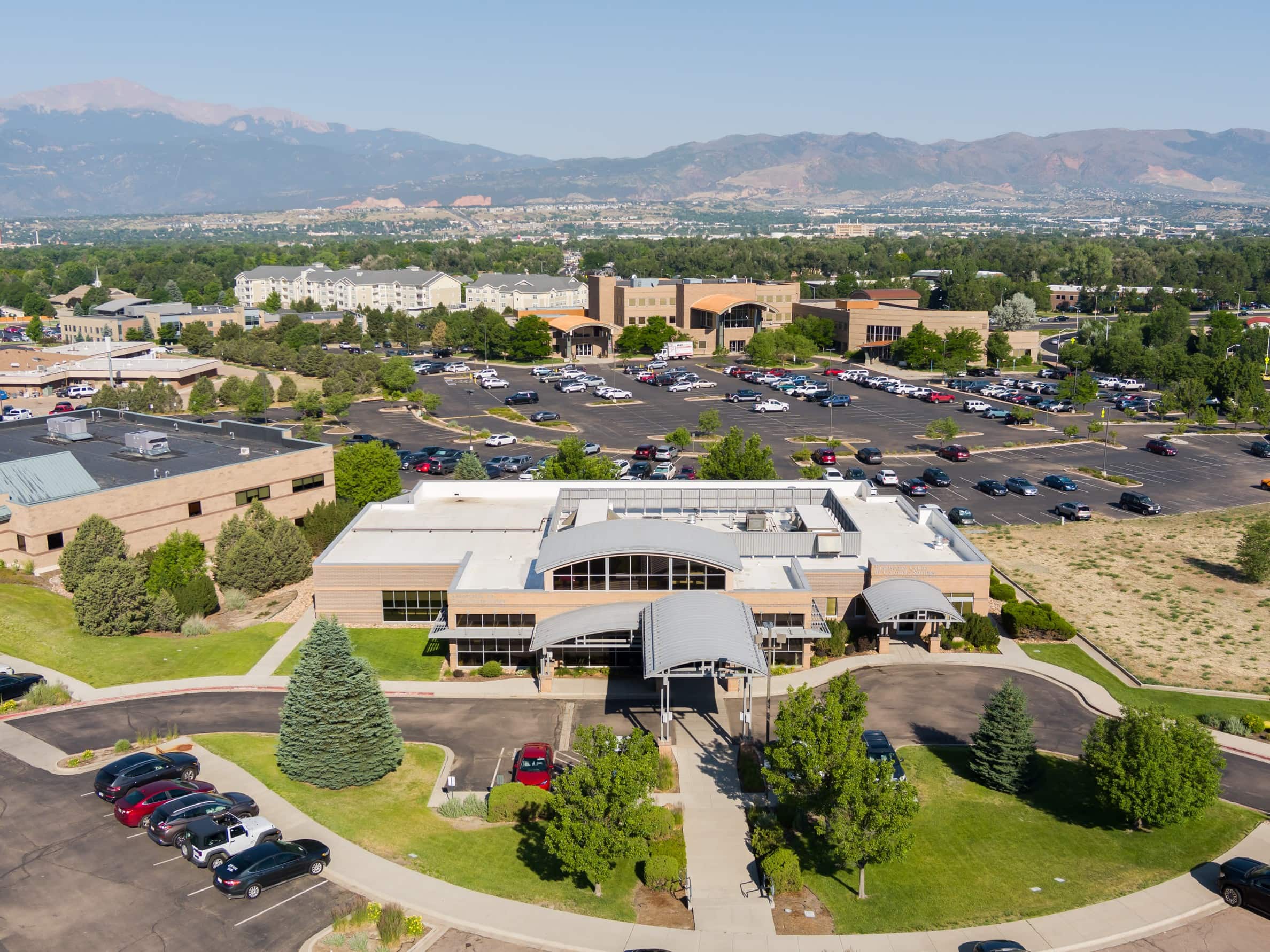 Aerial view of a suburban office complex and parking lot with mountain ranges in the background.