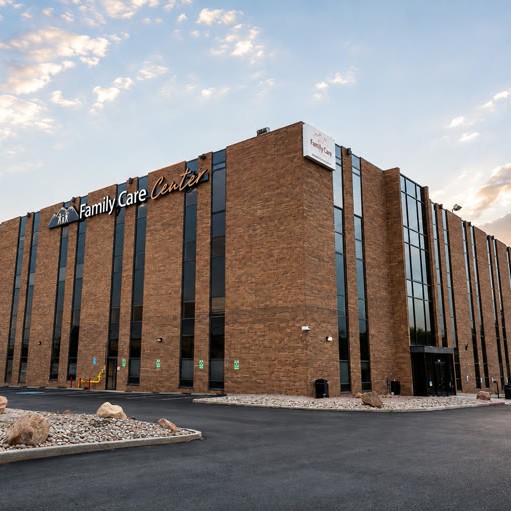 A multi-story brick building with tall windows and a sign reading “Family Care Center.”.